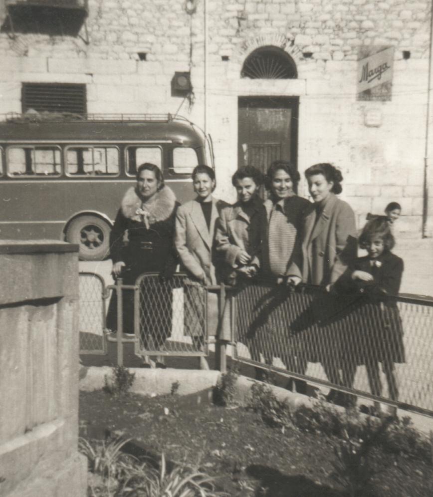 Gruppo di donne in posa di fronte l'aiuola della fontana di piazza Margherita